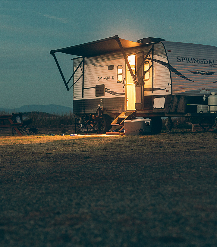 Caravan parked on the hill in the evening, lights coming from the vehicle.